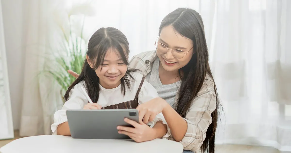 Người phụ nữ và bé gái cùng dùng máy tính bảng ở nhà