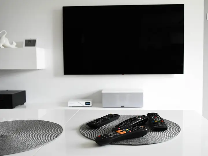 Phòng khách có tivi treo tường, điều khiển đặt trên bàn